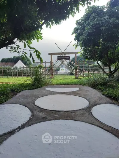 Charming garden pathway leading to a rustic wooden entrance, surrounded by lush greenery and serene outdoor ambiance.