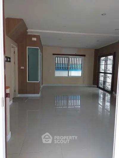 Spacious empty living room with large windows and glossy tiled floor