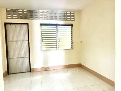Spacious empty room with tiled floor and natural light from window.
