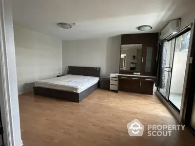 Spacious bedroom with large bed, ample natural light, and sleek wooden flooring, ideal for relaxation and comfort in a modern home.