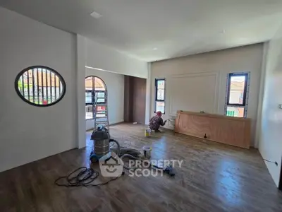 Spacious living room with wooden flooring and unique circular window design