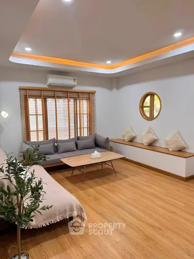 Modern living room with stylish furniture and wooden flooring, featuring a cozy seating area and ambient lighting.