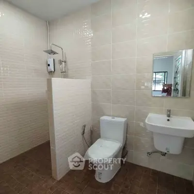 Modern bathroom with shower, toilet, and sink in a tiled setting.