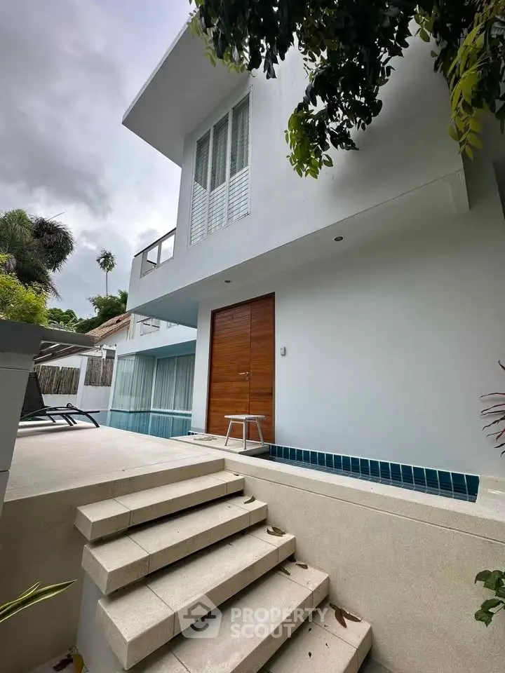 Modern white exterior of a luxury home with pool and stylish entrance, perfect for tropical living.