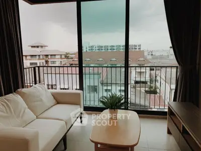 Cozy living room with balcony view overlooking urban landscape.