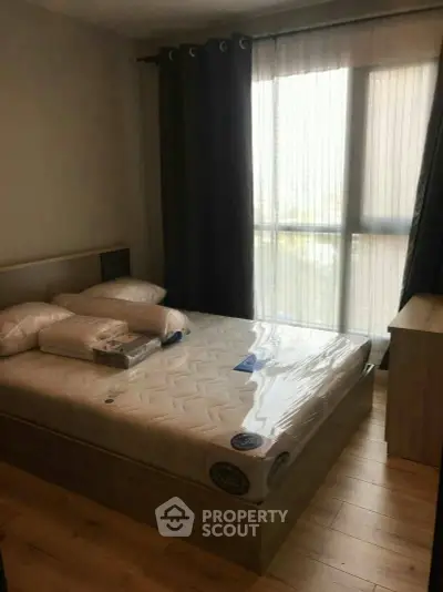 Cozy bedroom with large window and modern furnishings, perfect for relaxation.