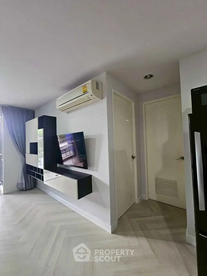 Modern living room with sleek entertainment unit and air conditioning in a stylish apartment.
