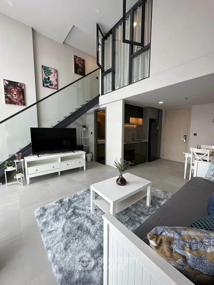 Modern duplex living room with stylish decor and high ceilings, featuring a cozy seating area and elegant staircase.