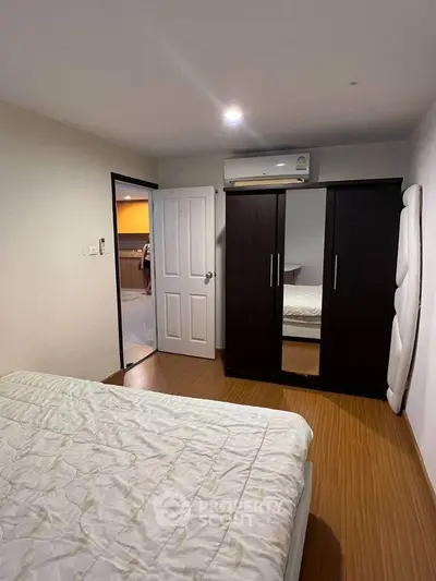 Cozy bedroom with wooden flooring and mirrored wardrobe in modern apartment.