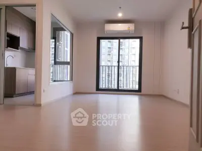 Spacious modern living room with large window and kitchen view