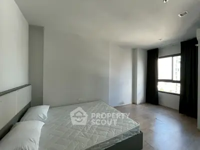 Spacious bedroom with large window and minimalist design in modern apartment.
