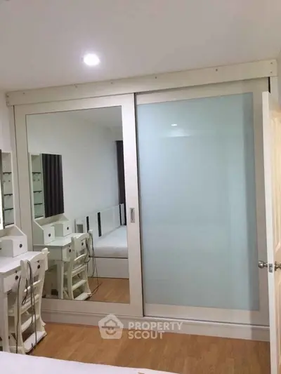 Modern bedroom with mirrored sliding closet doors and elegant vanity setup.