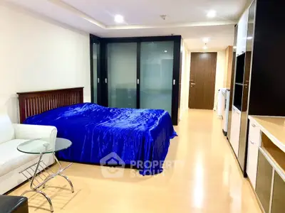 Modern studio apartment with sleek furnishings and vibrant blue bedding, featuring a cozy living space and contemporary design.