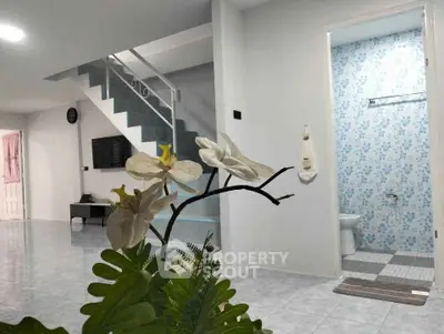 Modern interior with open living space and staircase, featuring a glimpse of a stylish bathroom.