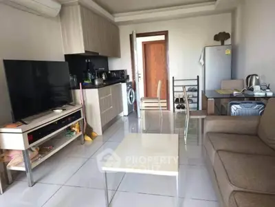 Modern living room with open kitchen, featuring sleek appliances and cozy seating area.