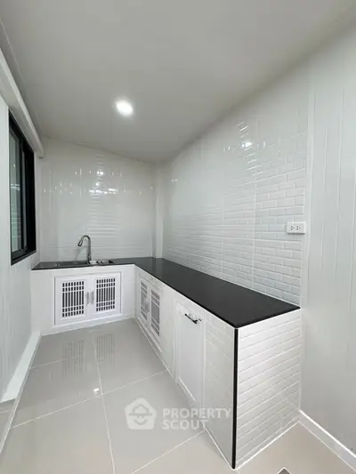 Modern kitchen with sleek black countertops and white tiled walls
