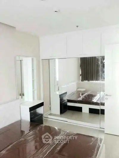 Modern bedroom with mirrored wardrobe and sleek furniture in a stylish apartment.