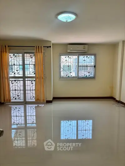 Spacious living room with glossy tiled floors and large windows, perfect for natural light.