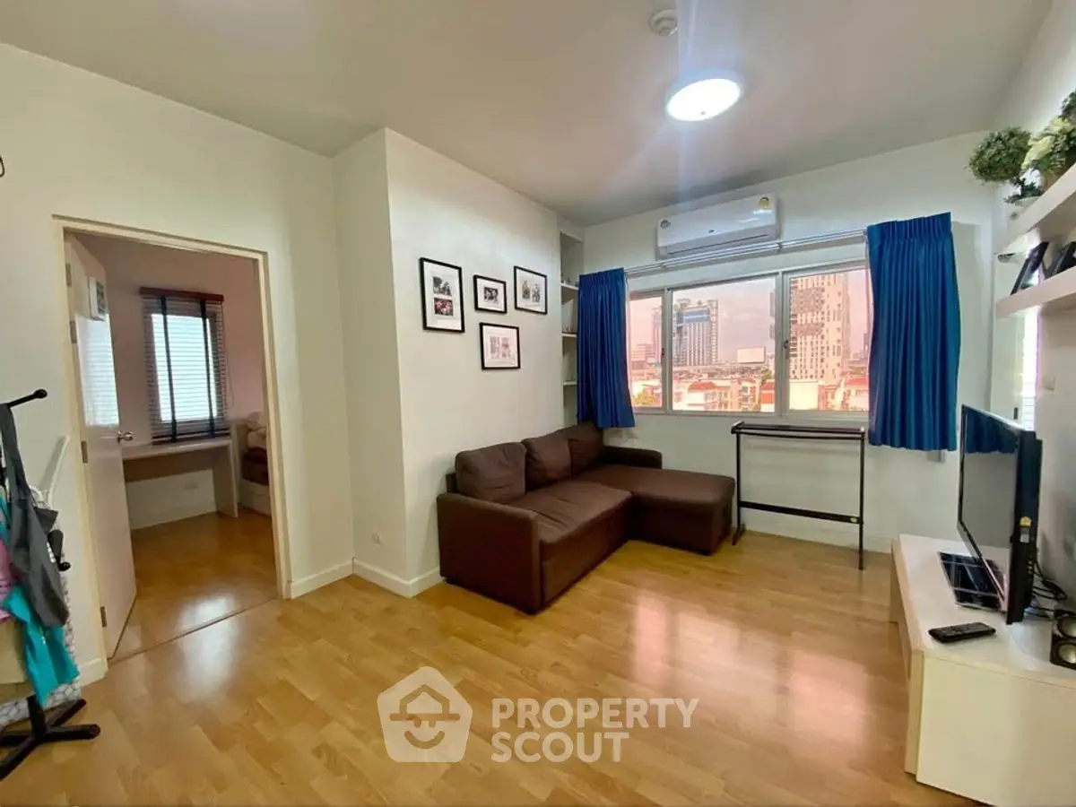 Cozy living room with wooden flooring, brown sofa, and city view window in modern apartment.