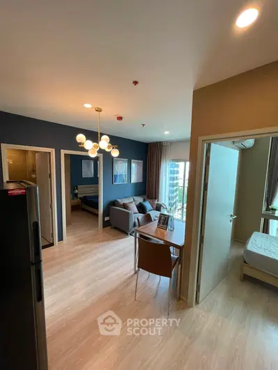 Modern apartment interior with open living room and bedroom, featuring stylish lighting and wooden flooring.
