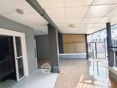 Spacious covered patio with tiled flooring and gated entrance, ideal for outdoor relaxation.