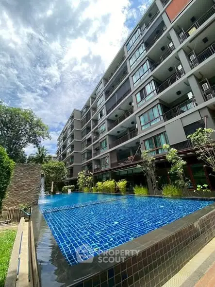 Modern apartment building with a stunning outdoor pool and lush greenery.