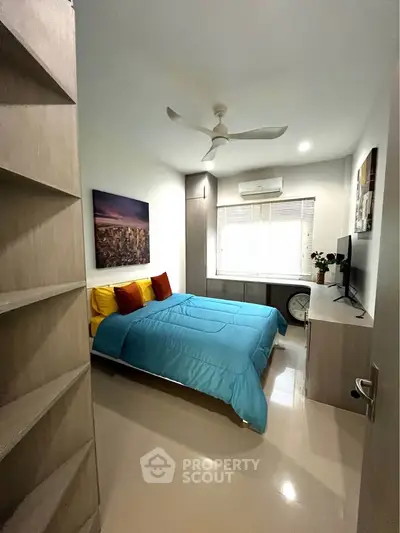 Cozy bedroom with modern decor, vibrant bedding, and ample natural light.