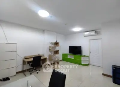 Modern living room with sleek furniture and bright lighting, featuring a TV and workspace.
