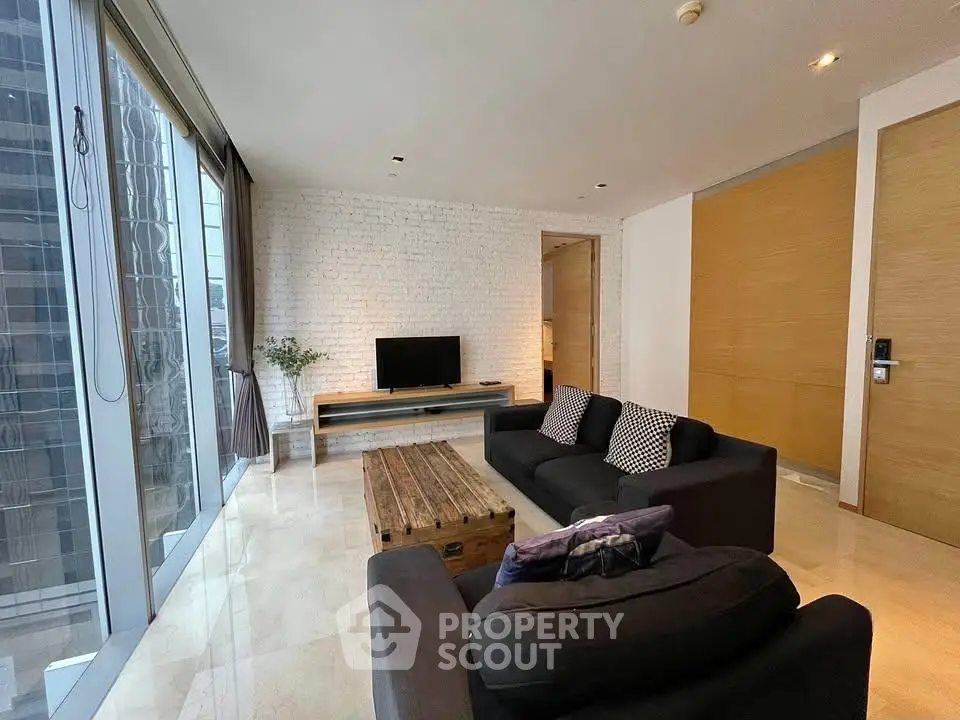 Modern living room with large windows and stylish furniture in a high-rise apartment.