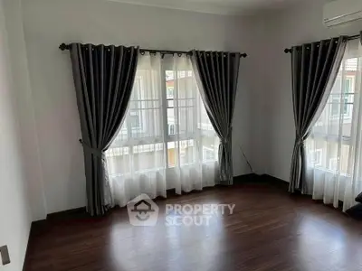 Spacious corner unit with elegant curtains and hardwood floors