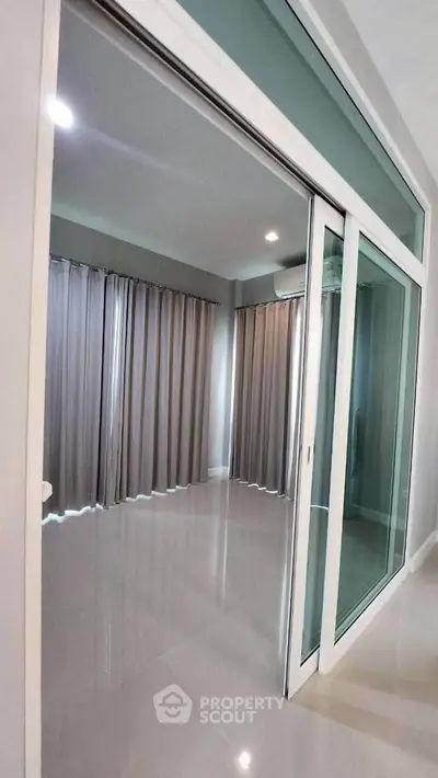 Spacious modern room with large sliding glass doors and elegant curtains, perfect for versatile living space.