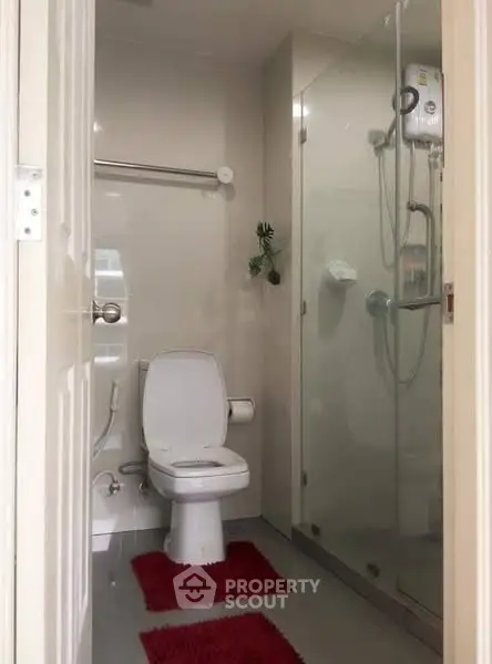 Modern bathroom with glass shower and red rugs