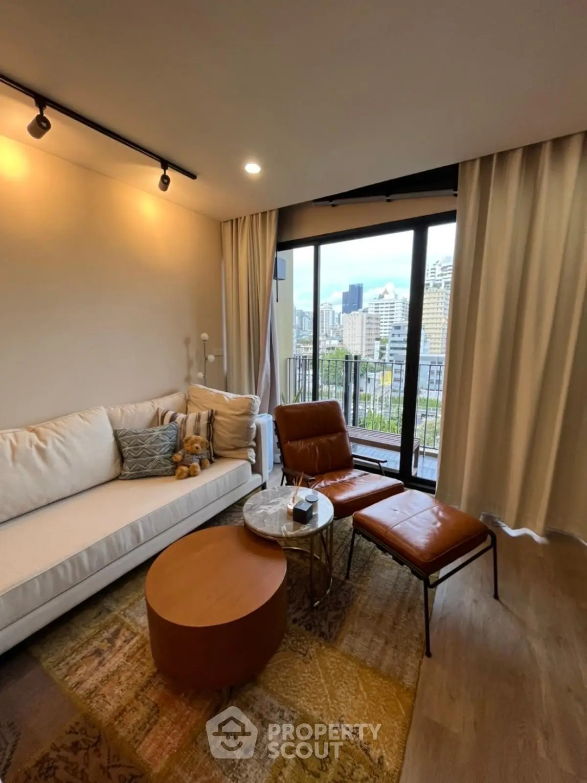 Modern living room with city view, stylish furniture, and floor-to-ceiling windows in urban apartment.