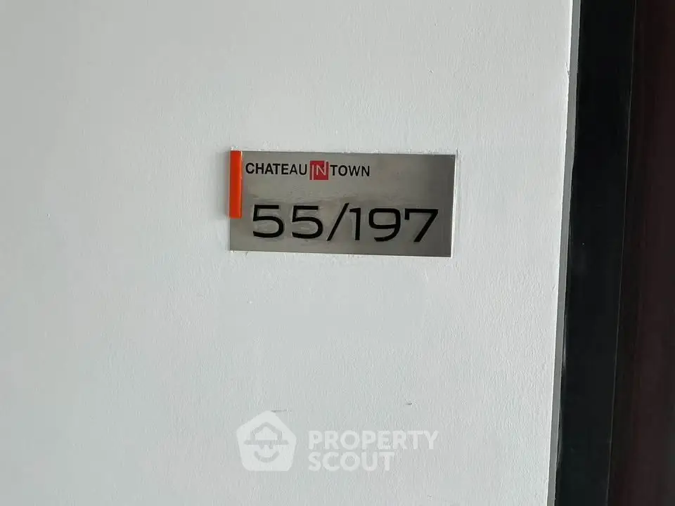 Modern apartment unit number sign on a white wall, indicating property address.