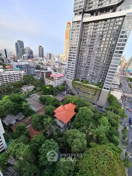 Stunning cityscape view from high-rise building overlooking lush greenery and urban skyline.