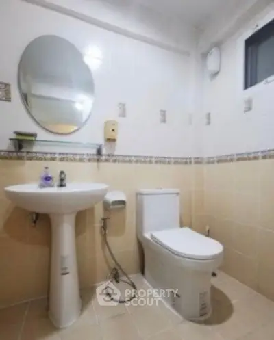 Modern bathroom with pedestal sink and round mirror in a cozy apartment.