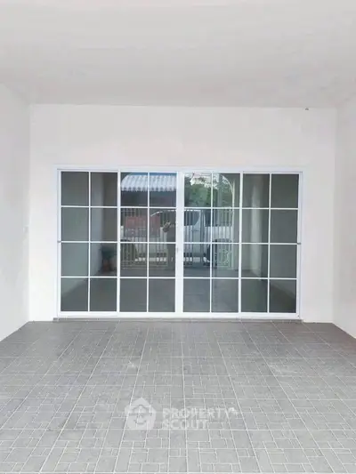 Spacious garage with sliding glass doors and tiled flooring, perfect for versatile use.