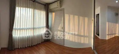 Bright empty room with wooden flooring and large window, perfect for customization.