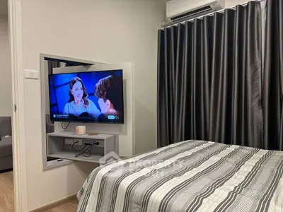 Modern bedroom with wall-mounted TV and stylish curtains, perfect for cozy living.
