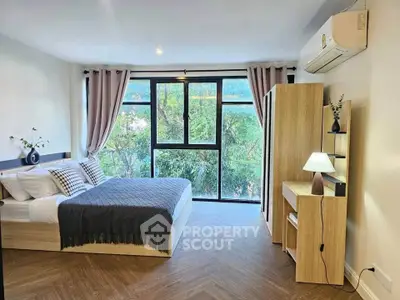 Modern bedroom with large window and stylish decor, featuring a cozy bed and wooden furniture.