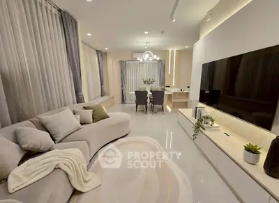 Modern living room with elegant decor and large TV, perfect for relaxation and entertainment.