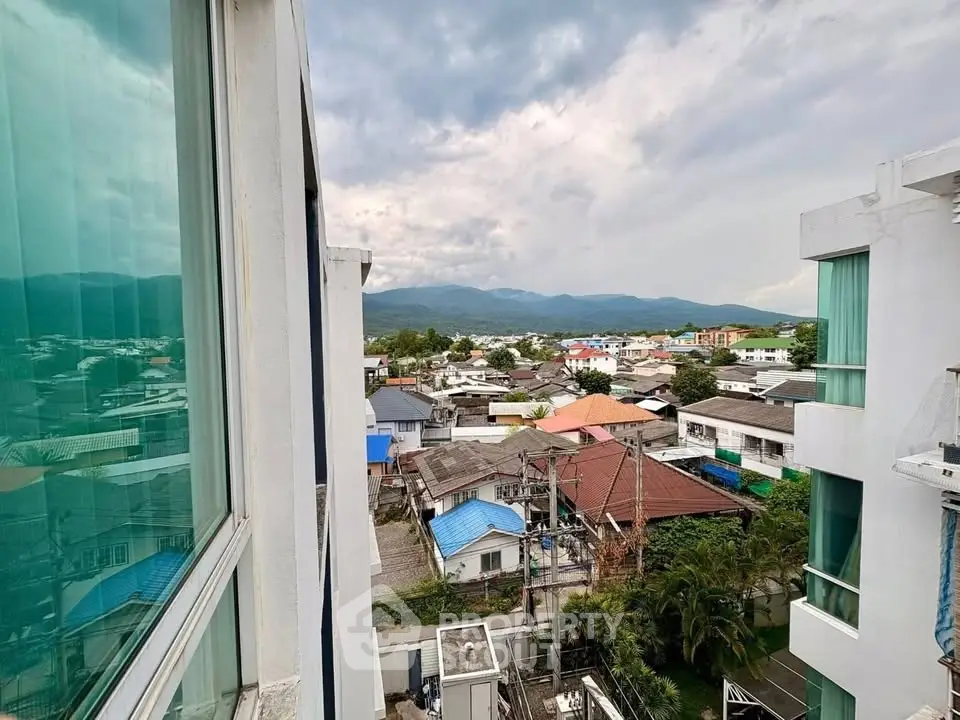 Stunning view from a modern apartment overlooking a vibrant neighborhood and distant mountains.