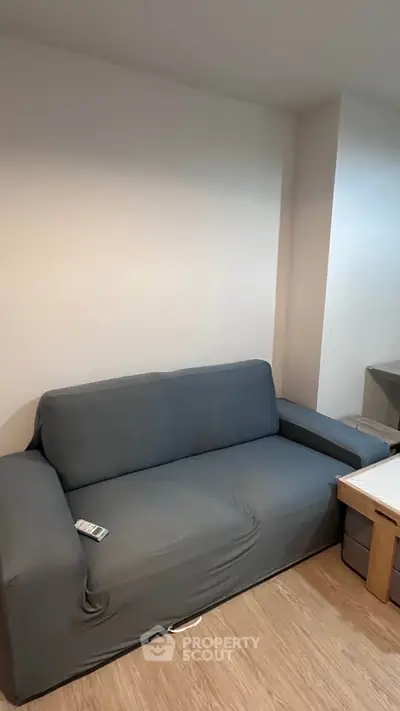 Cozy living room with modern gray sofa and wooden flooring, perfect for relaxation.