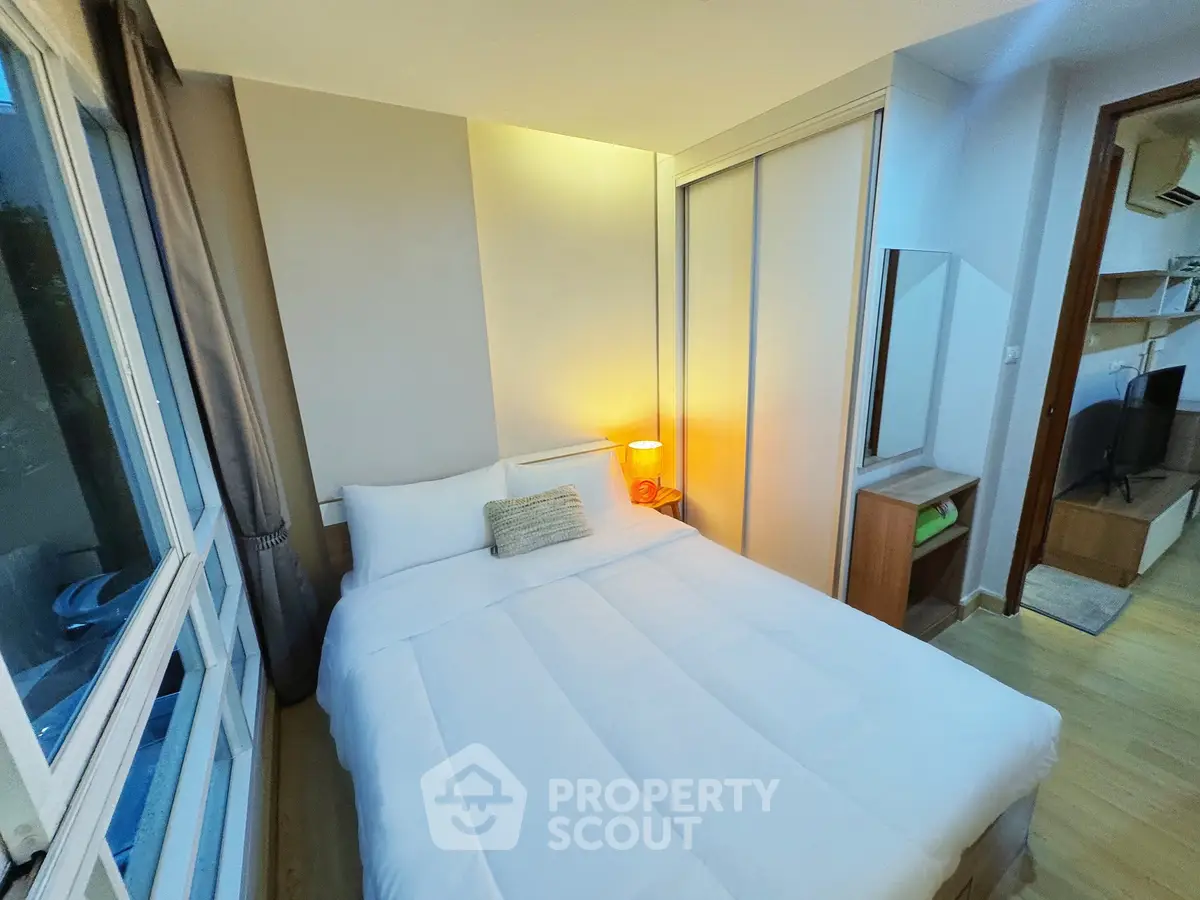 Cozy bedroom with large window and modern furnishings, perfect for relaxation.