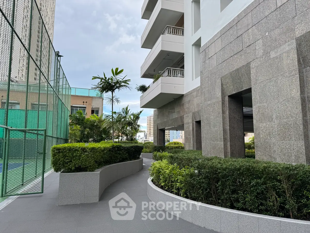 Modern building exterior with lush greenery and tennis court view