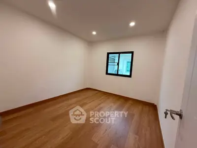 Spacious empty room with wooden flooring and a window, perfect for customization.
