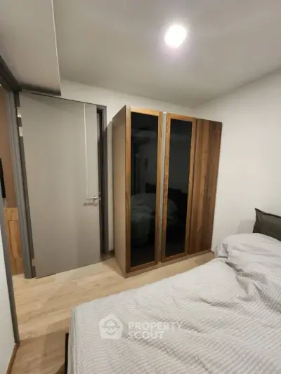 Modern bedroom with sleek wardrobe and cozy bedding in stylish apartment.