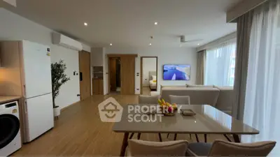 Modern open-plan living room with dining area, featuring sleek furniture and natural light.