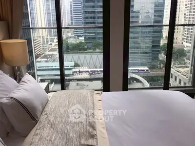 Luxurious bedroom with stunning city view from high-rise window.