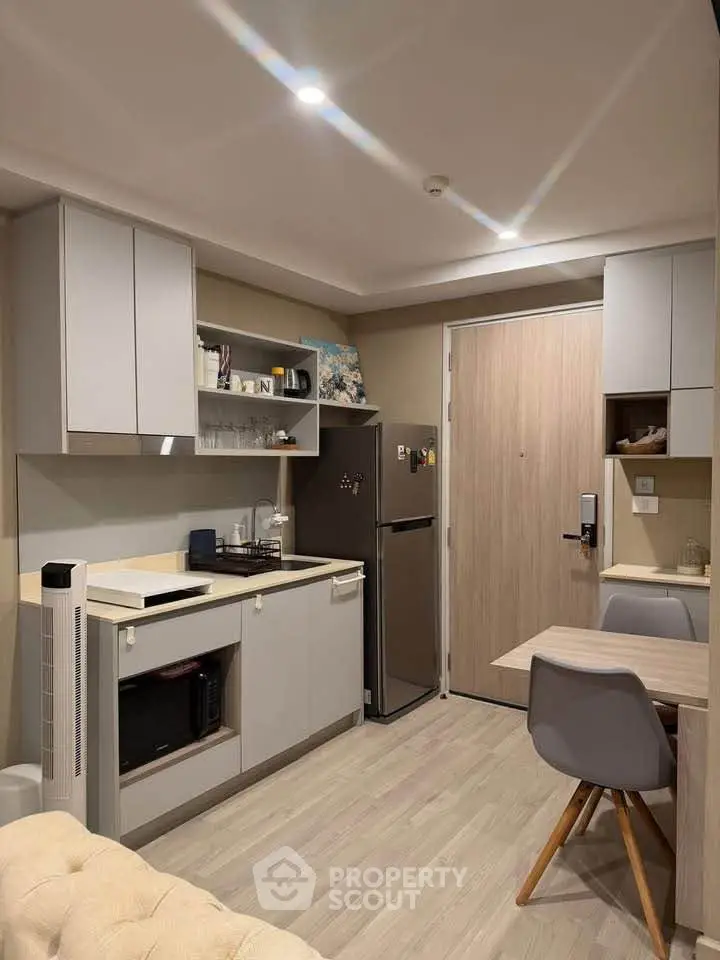 Modern compact kitchen with sleek cabinetry and dining area in cozy apartment.